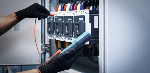 Electrical engineer tests the operation of the electric control cabinet on a regular basis for maintenance.