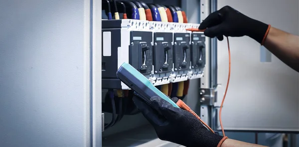 Electrical engineer tests the operation of the electric control cabinet on a regular basis for maintenance.