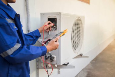 Technician checking the operation of the air conditioner. clipart
