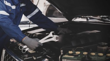Tamirci garajdaki arabanın motoru üzerinde çalışıyor. Araba teftiş hizmeti ve araba tamir hizmeti kavramı..