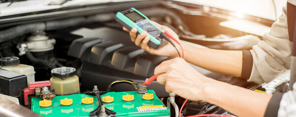 Техник проверяет наличие аккумулятора в машине..;