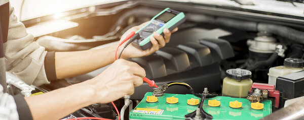 Техник проверяет наличие аккумулятора в машине..;