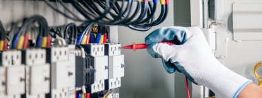 Electrical engineer checking the operation of electrical control cabinet, maintenance concept.