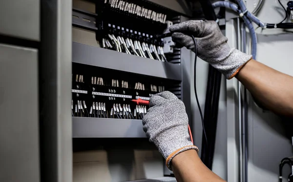 Electrical engineer tests the operation of the electric control cabinet on a regular basis for maintenance.