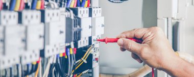 Electrical engineer checking the operation of electrical control cabinet, maintenance concept.