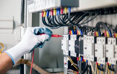 An electrical engineer is inspecting the operation of an electrical control cabinet. maintenance concept