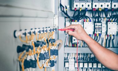 An electrical engineer is inspecting the operation of an electrical control cabinet. maintenance concept