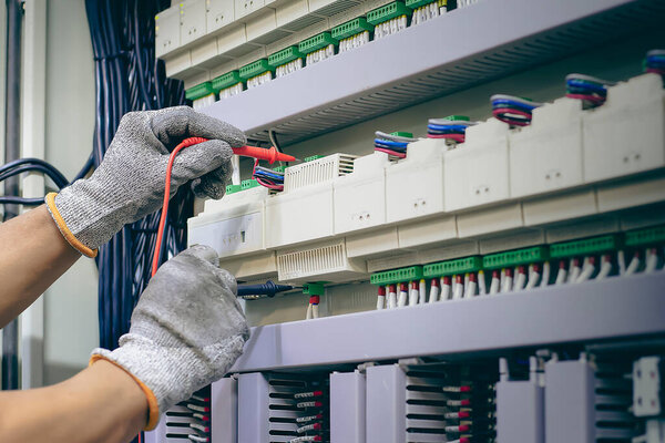 An electrical engineer is inspecting the operation of an electrical control cabinet. maintenance concept