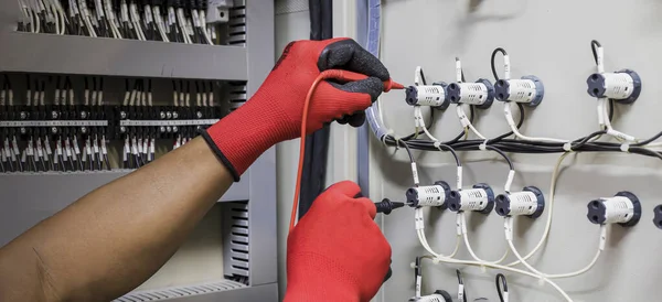 Electrical engineer tests the operation of the electric control cabinet on a regular basis for maintenance.