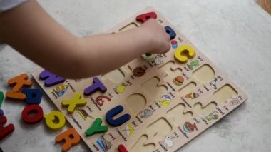 Top view of a kid playing alphabet puzzle and learning English on the floor.