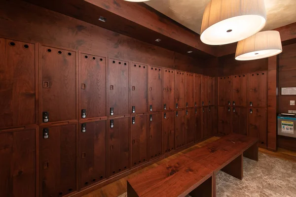 Interior of a locker room. Clean empty dressing room with big lockers with wooden door and wooden bench