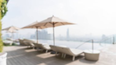 Plaj sandalyesi, şemsiye, mavi gökyüzü ve bulanık şehir manzaralı şehir manzaralı havuz manzaralı havuz partisi için otel çatı katında yaz havuzu arka planı.