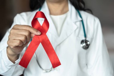 Dünya AIDS 'e ve ulusal HIV AIDS' e ve yaşlanmakta olan farkındalık ayına tıbbi veya cerrahi doktorların elinde kırmızı kurdele ile yardım ediyor 