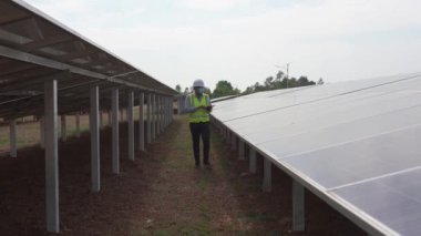 Güneş enerjisi üretimi için güneş panellerini inceleyen mühendislerin uzun çekim görüntüleri.