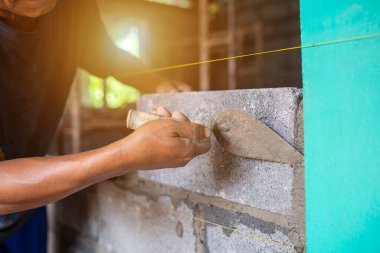 Close-up shot of a bricklayer building a house or walls with mortar and bricks