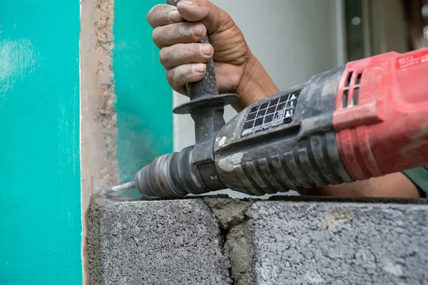 Technicians use a drill to drill holes in the masonry to strengthen the structure in the construction.