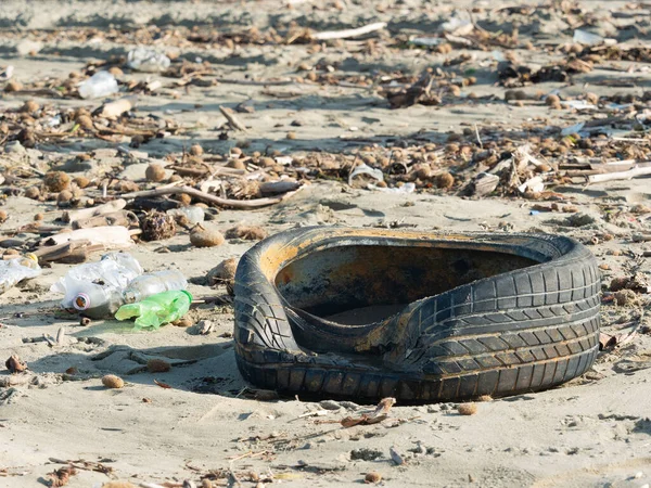 Tire, plastic bottles and other garbage left on the beach after a storm, a symbol of serious pollution of the seas and ocean
