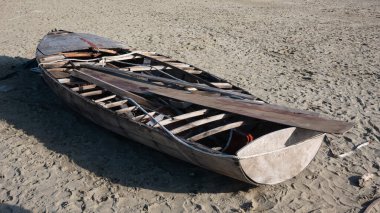hull of a shipwrecked small sailboat on the beach. It is possible to see the rough wooden structure 