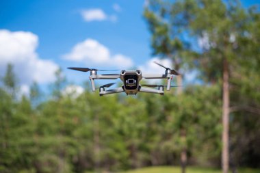 Mavi gökyüzünde uçan bir dron. Kameralı modern kompakt drone. Arkaplan kavramı.