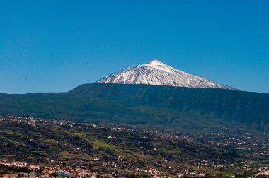 Kar kaplı Teide, Orotava Vadisi 'ne hükmediyor. Mavi gökyüzü arka planına sahip. Kış gelmiş gibi görünmüyor.