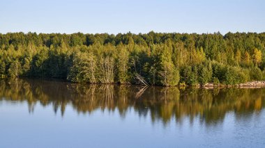 - Rusya. Gün batımında Volga-Baltık kanalının Kovzha nehri. Nehrin pürüzsüz yüzeyindeki kıyıların ayna yansıması.