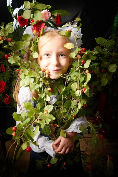 Girl who is elementary school children in uniform having photo shoot in school holiday on September 1 on black background with flowers. Holiday of the beginning of school and studing in Russia