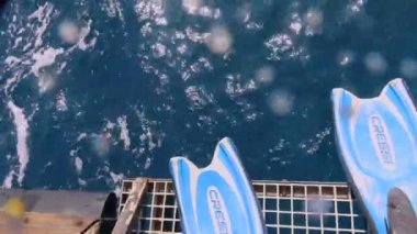 Mısır 'da, Kızıldeniz' de bir dalış teknesinin arkasından suya dalan bir dalgıcın 4K video görüntüsü.