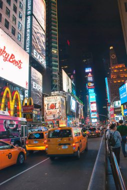 Time Square, New York çevresindeki uzun binalar ve parlak ışıklar.