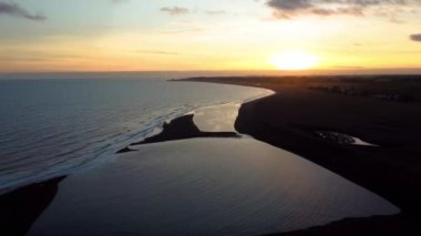 Güneş 'in Suffolk, İngiltere' deki Shingle Caddesi 'nde batarken 4k drone görüntüsü.