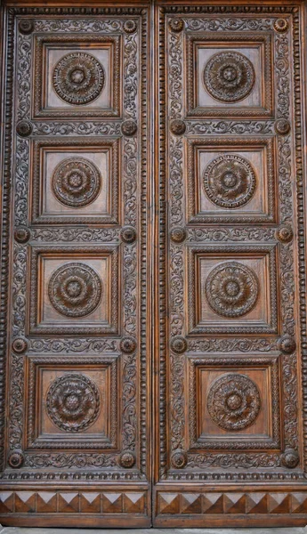 Ancient solid wood doors with hand-carved decorations by local artists, in the splendid historic center of Lucca