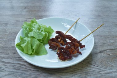  Kızarmış et, ahşap sopa ve sebze bıçaklıyor.