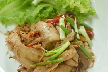  Baharatlı kızarmış tavuk eti ve kırmızı biber soslu taze soğan, tabakta marul.