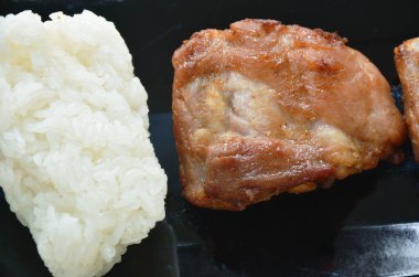  Kızarmış domuz kemiği. Siyah tabakta birkaç tane yapışkan pirinç ye.