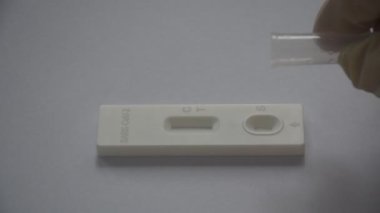 Kauçuk eldiven, tüpten antijen test kitine sıvı örnekleme kimyasalı bırakın beyaz arka planda COVID-19 veya coronavirüs kontrolü için