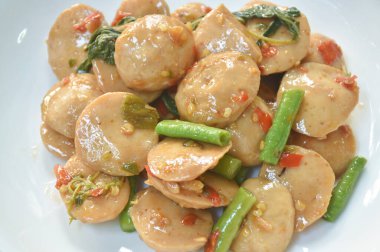  Baharatlı kızarmış domuz eti köftesi, yanında fasulye ve tabakta fesleğen yaprağı.