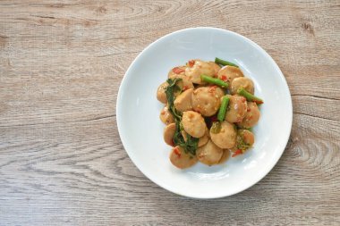  Baharatlı kızarmış domuz eti köftesi, yanında fasulye ve tabakta fesleğen yaprağı.