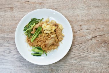  Kızarmış vermicelli ince pirinç eriştesi dilimlenmiş domuz eti ve Çin lahanası soslu siyah soya fasulyesi sosu tabakta.