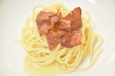  Kızarmış domuz pastırmasının üzerine beyaz soslu spagetti.