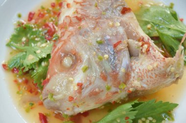  Acı biber ve limon soslu buğulanmış mango balığı kafası. Tabakta kereviz.