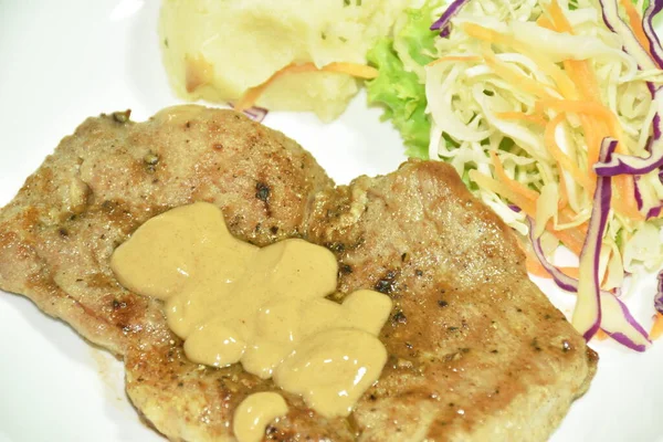 grilled pork black pepper steak with mashed potato and salad dressing gravy sauce on plate
