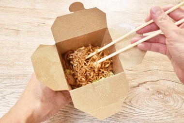  Kızarmış yakisoba Japon eriştesi dilimlenmiş domuz pastırması ve lahana kutuda ahşap çubuklarla yenir.