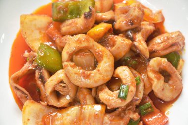  Dilimlenmiş biberli kızarmış kalamar ve tabakta tatlı ve ekşi soslu soğan.