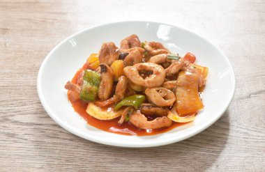  Dilimlenmiş biberli kızarmış kalamar ve tabakta tatlı ve ekşi soslu soğan.