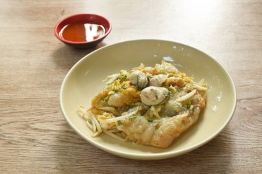 Kızarmış istiridye, yumurta omleti ve fasulye filizi tabakta, acı sos.