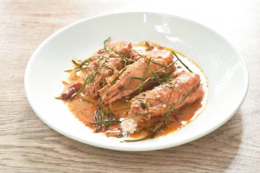 Baharatlı kızarmış nehir karidesi ve dilimlenmiş yeşil yapraklı köri tabağı. 