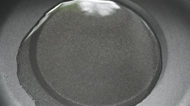 silver chopsticks picking raw bacon to fried in hot oil in pan