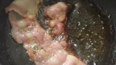 fried pork bacon and egg in hot oil on electric pan