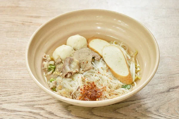 vermicelli rice noodles topping chop boiled pork and fish ball in soup dressing cayenne pepper on bowl