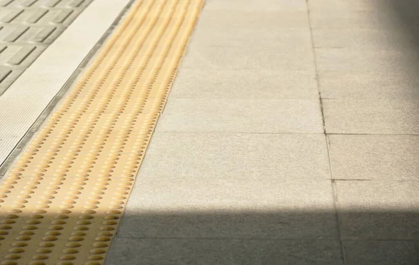 yellow security line in train station floor with shadow on sunlight