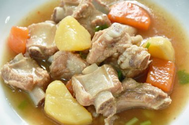 boiled pork bone with potato and carrot stew on plate